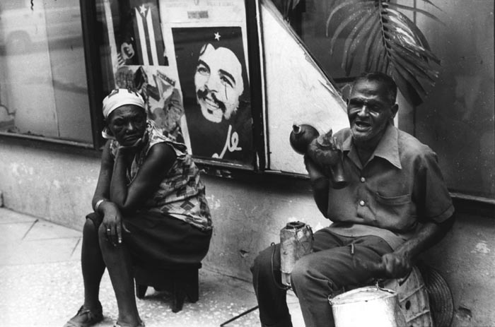 Eddy Garaicoa - Man Making Music on Street and Woman Sitting Beside Him, Cuba