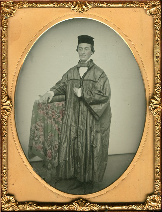 Young Academic Wearing Robe, Posed Beside a Large Book
